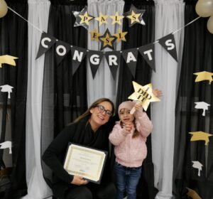 photo of mother and daughter celebrating the graduation from English language course at literacy coalition of central texas. the mother and daughter are smiling and holding a certification and an I did it sign.